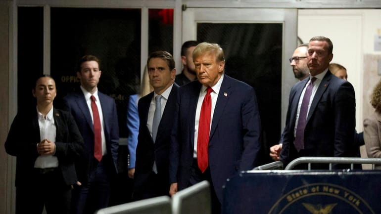 Former President and Republican presidential candidate Donald Trump, center, leaves...