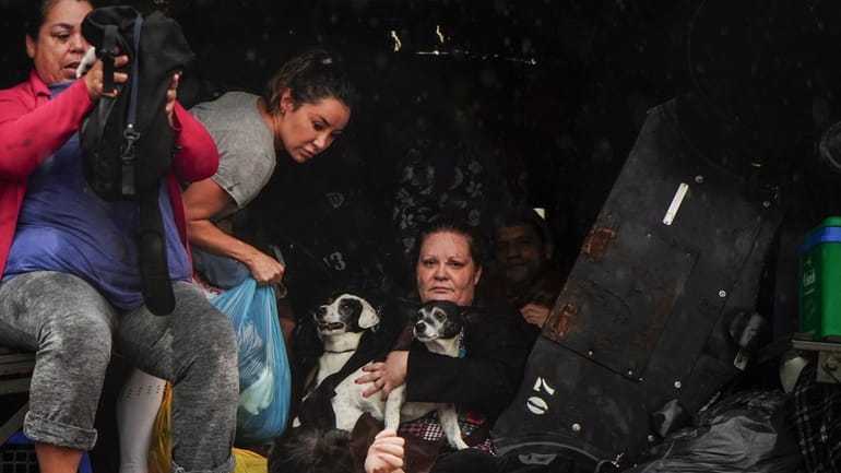 People and their pets evacuate a flooded area after heavy...